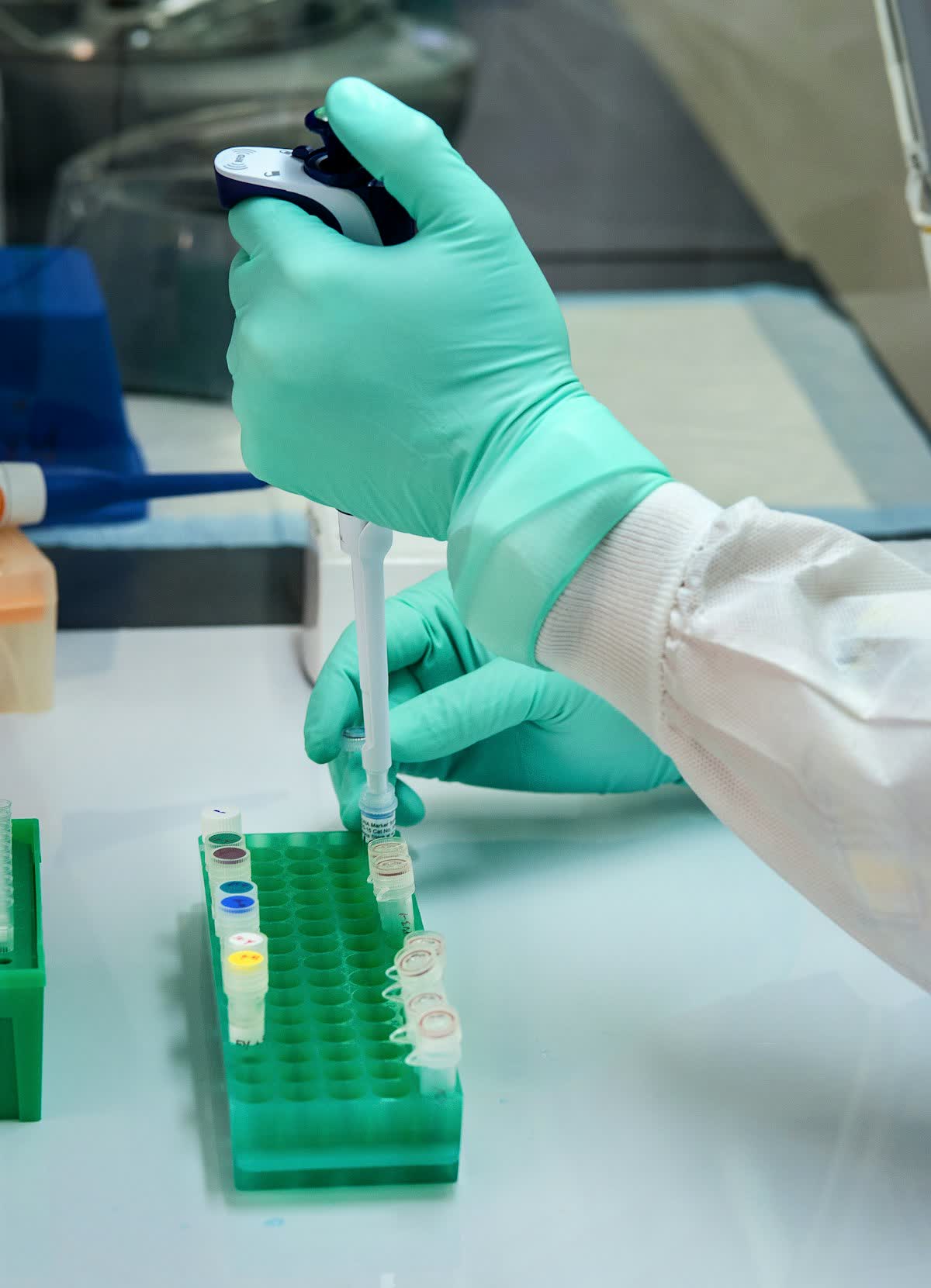 Gloved hands pipetting samples in a QC laboratory